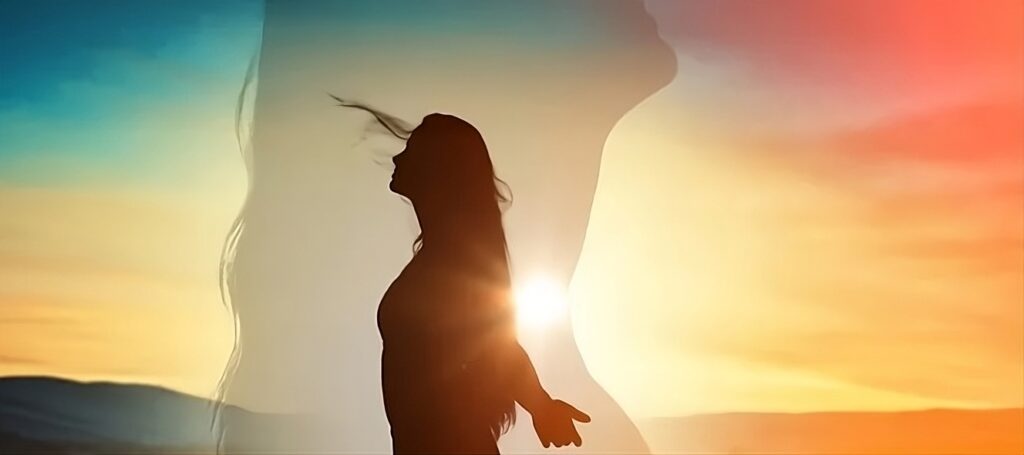 A imagem mostra o desenho de uma mulher de braços abertos na frente de um sol, sobreposta pela imagem em close dessa mesma mulher, simbolizando o sabotador, a voz interna crítica que nos faz adiar ou desistir de ações